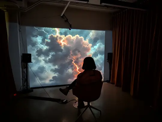 A visitor sitting in front of a projected, AI-generated stormy sky in Reflet